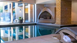 Indoor pool with comfortable seating and views to the courtyard - Hatherley Manor Hotel & Spa, Cotswolds