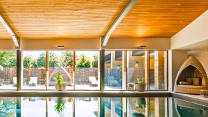Indoor pool with comfortable seating and views to the courtyard - Hatherley Manor Hotel & Spa, Cotswolds