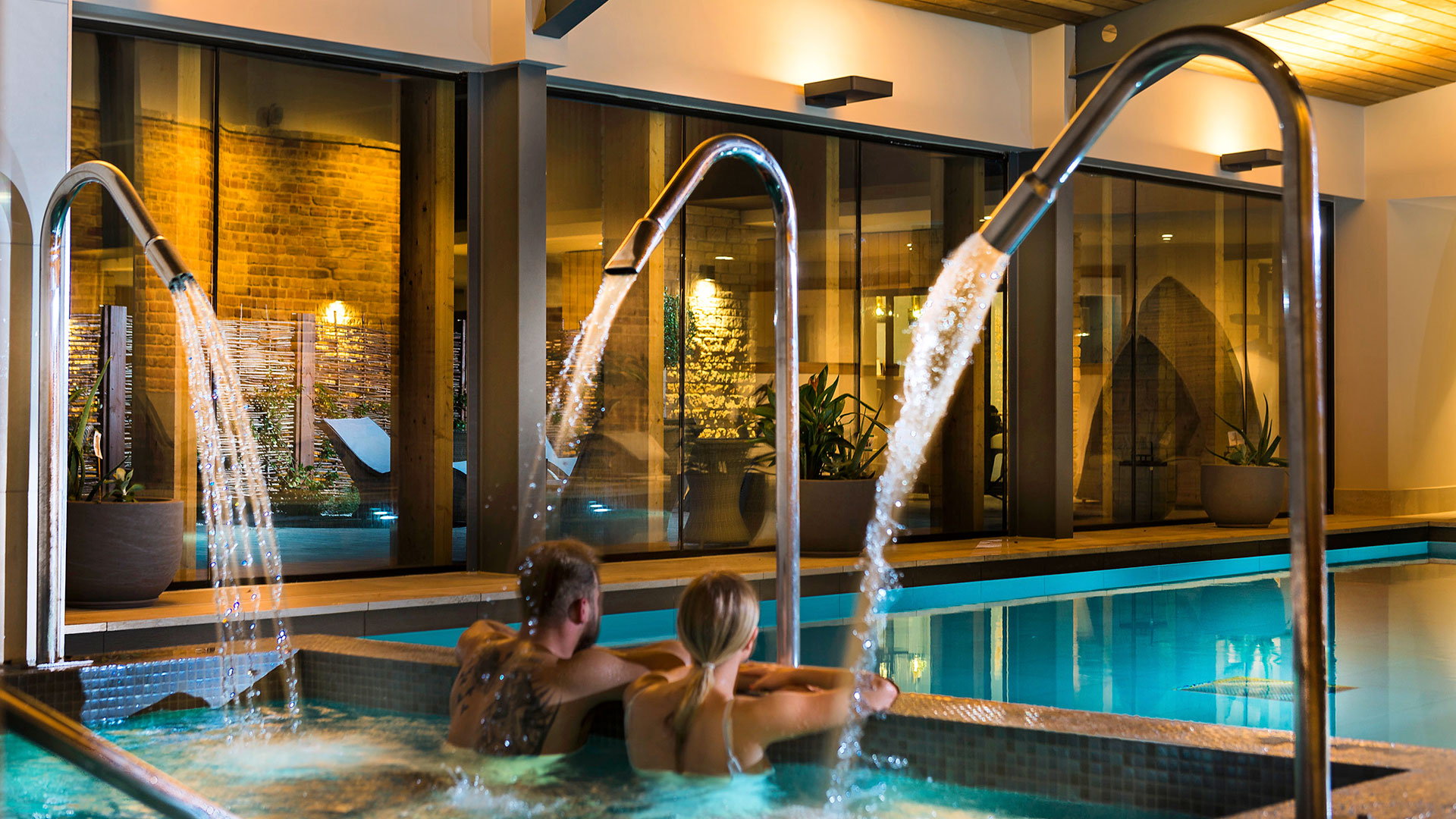A couple relaxing in the Vitality pool with water jets - Hatherley Manor Hotel & Spa, Cotswolds