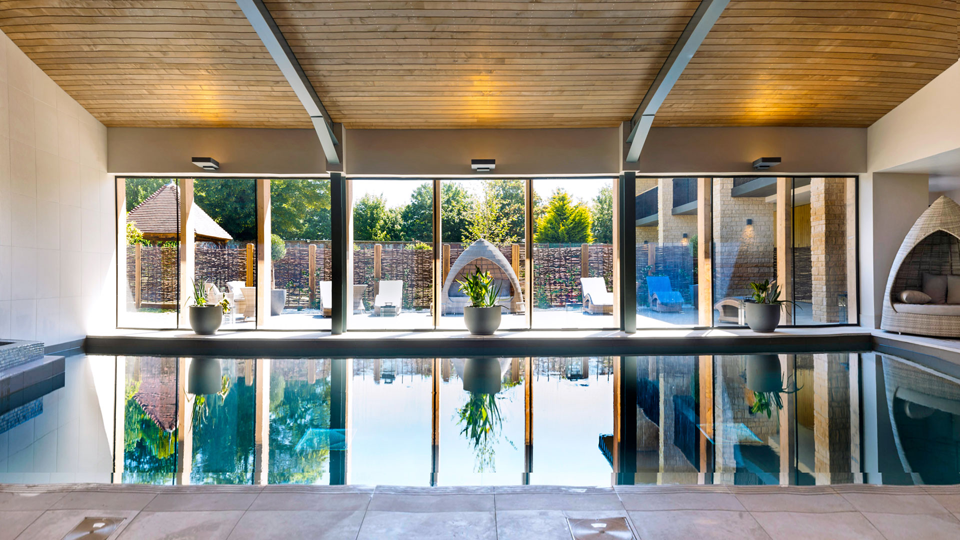 Indoor pool with comfortable seating and views to the courtyard - Hatherley Manor Hotel & Spa, Cotswolds