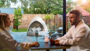 A couple relaxing with a glass of Champagne in the Spa Cafe, overlooking the garden - Hatherley Manor Hotel & Spa, Cotswolds