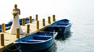 A newlywed bride on the jetty surrounded by boats - Frensham Pond Country House Hotel & Spa, Farnham