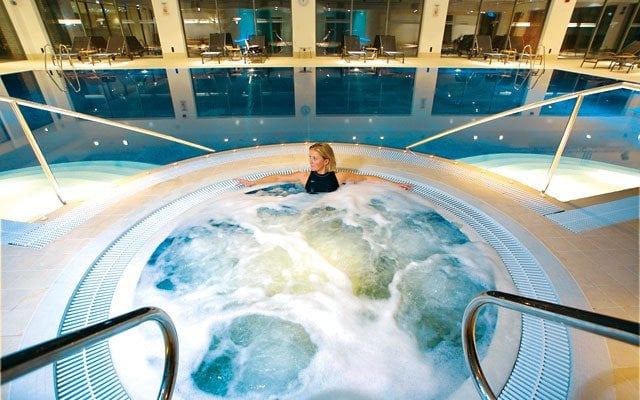 A woman relaxing in the hot tub with views over the swimming pool - Donnington Valley Hotel, Golf & Spa, Newbury