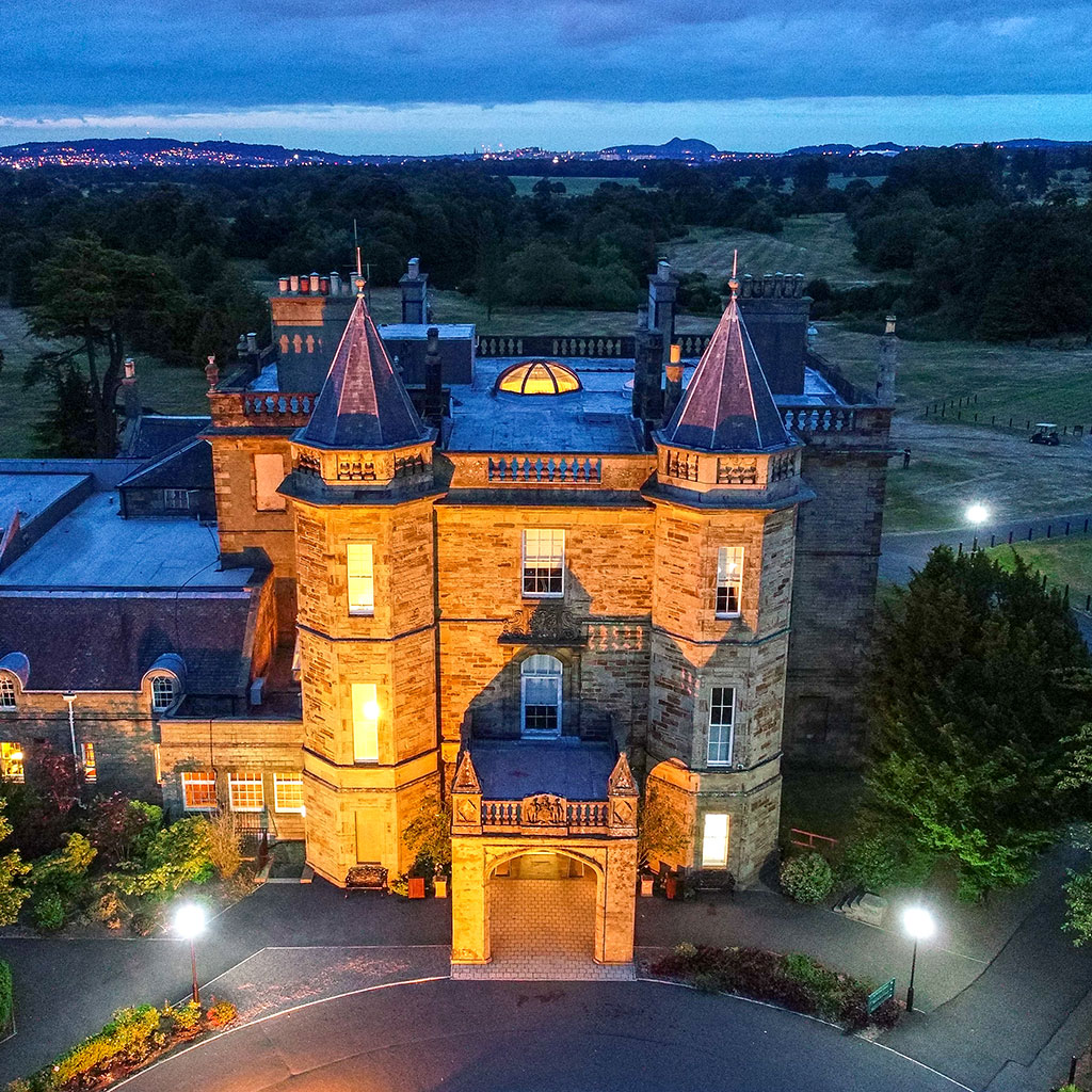 The turrets of the hotel illuminated at dusk - Dalmahoy Hotel & Country Club, Edinburgh